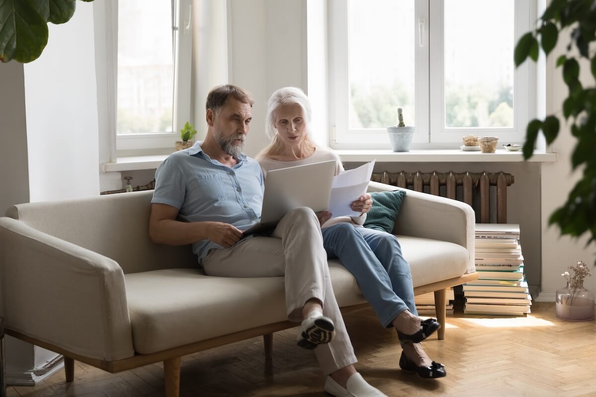 Couple of older adults sitting at home going through their bills