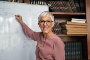 Older woman teaching on a whiteboard.